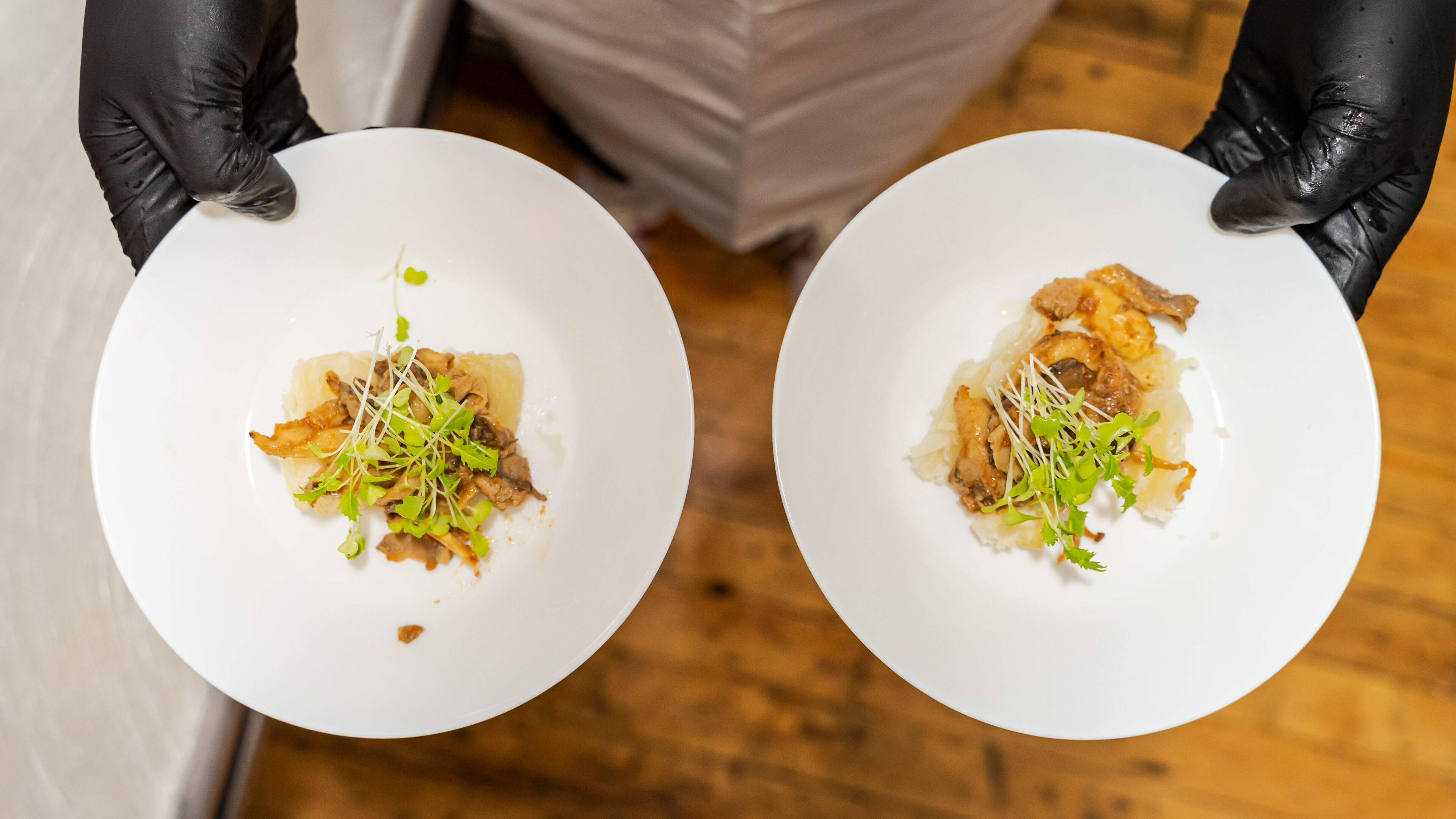 a chef holding two tasty plates of african cuisine