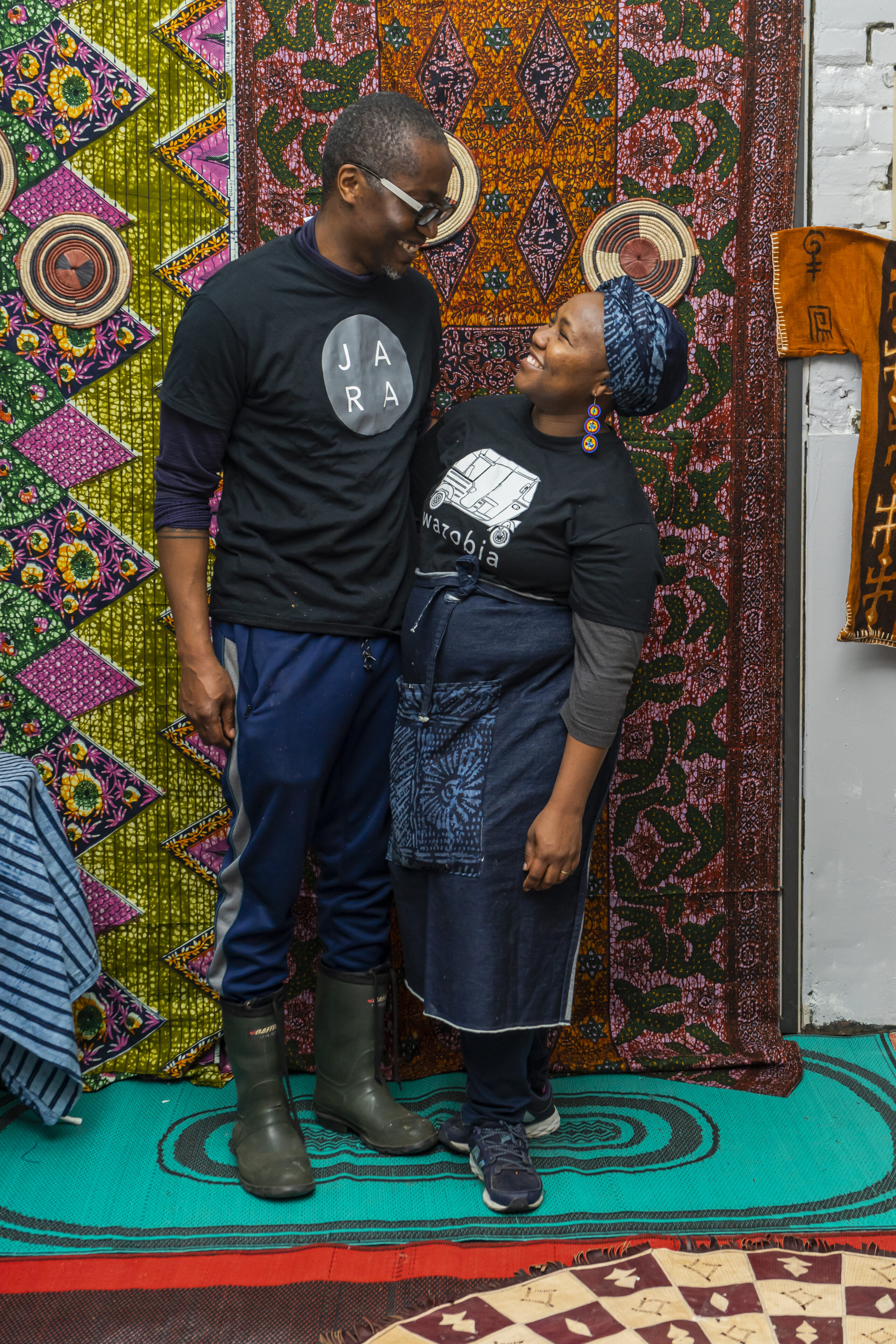 two cooks smiling in front of a colourful backdrop